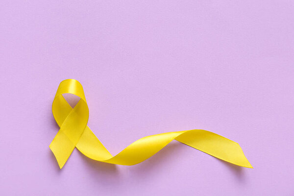 Golden ribbon on lilac background. Children cancer awareness concept