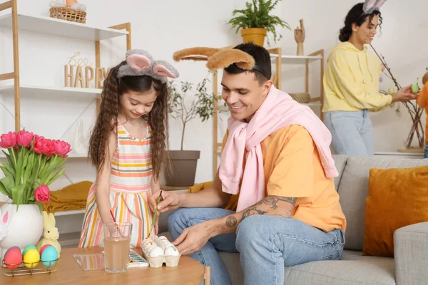 Mutlu bir baba ve küçük kızı Paskalya günü evde yumurta boyuyor.