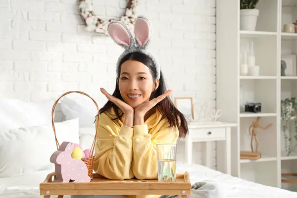 Yatak odasında tavşan kulaklı ve paskalya yumurtalı genç Asyalı kadın.