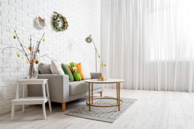 Paskalya çelenkleri ve kanepesi olan bir oturma odası.