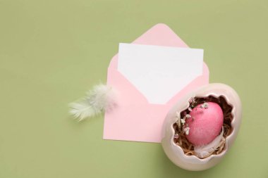 Yeşil arka planda boş kart, yumurta ve tüylü kompozisyon. Paskalya kutlaması