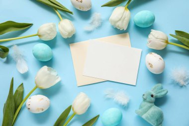 Mavi zemin üzerinde boş kart, lale ve Paskalya yumurtaları olan kompozisyon