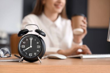 Ofisteki iş kadınının masasındaki çalar saat, yakın plan. Zaman yönetimi kavramı
