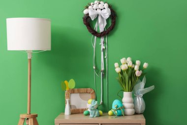 Yeşil duvarın yanındaki klozette lale ve Paskalya dekoru olan vazo.