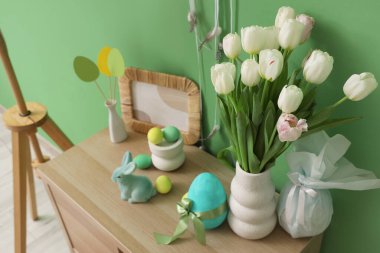 Yeşil duvarın yanındaki klozette lale ve Paskalya dekoru olan vazo.