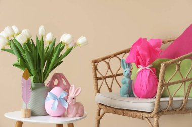 Odadaki bej duvarın yanındaki masada lale ve Paskalya dekoru olan vazo.