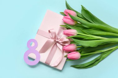 Hediye kutusu ve mavi arka planda güzel laleler olan kağıttan yapılmış 8 figür. Uluslararası Kadınlar Günü