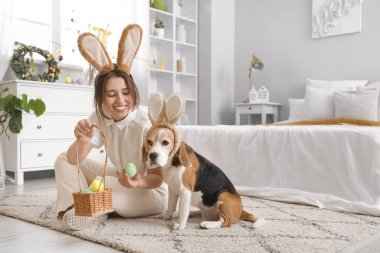 Yatak odasında Beagle köpeği ve Paskalya yumurtaları olan genç bir kadın.