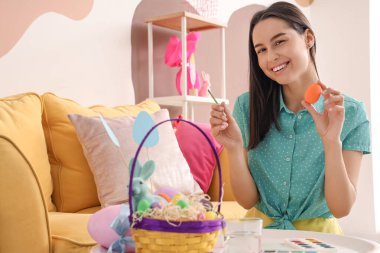 Evde Paskalya yumurtası boyayan genç bir kadın.