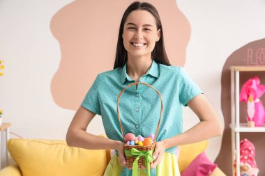 Evde paskalya yumurtası dolu sepeti olan genç bir kadın.