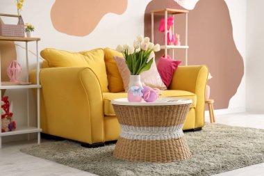 Oturma odasındaki masada lale ve Paskalya yumurtaları olan vazo.