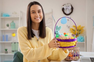 Evde paskalya yumurtası dolu sepeti olan genç bir kadın.
