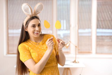 Tavşan kulaklı genç bir kadın. Evde paskalya yumurtaları var.
