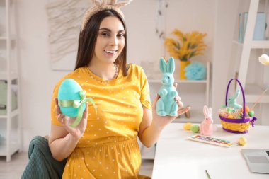 Evde Paskalya tavşanı ve yumurtası olan hamile bir kadın var.