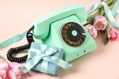 Hediye kutusu ve pembe arka planda güzel laleleri olan Retro telefon. Uluslararası Kadınlar Günü