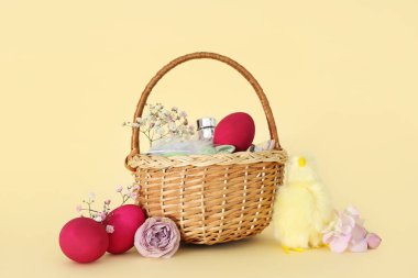 Süslü kozmetik sepetleri, Paskalya yumurtaları ve sarı arka planda bebek tavukları.