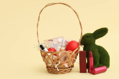 Süslü kozmetik sepetleri, sarı arka planda Paskalya yumurtaları ve tavşancık.