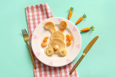 Turkuaz arka planda muzlu ve mandalinli komik Paskalya tavşanı krepleri.