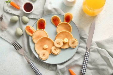 Açık mavi arka planda boyalı yumurtaları olan komik Paskalya tavşanı krepleri.