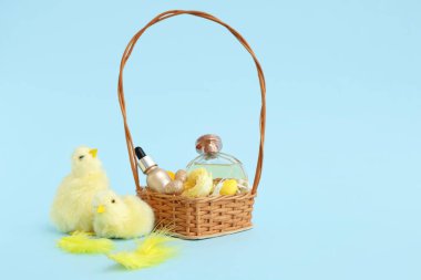 Süslü kozmetik sepetleri, paskalya yumurtaları ve mavi arka planda bebek tavukları.