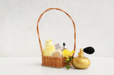 Dekoratif kozmetik ürünleri, beyaz arka planda bebek tavuk ve çiçeklerle dolu bir sepet.