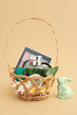 Bej arka planda dekoratif kozmetik ürünleriyle hasır Paskalya sepeti