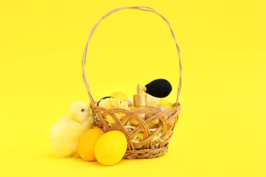 Süslü kozmetik sepetleri, Paskalya yumurtaları ve sarı arka planda bebek tavukları.