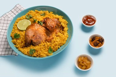 Mavi arka planda baharatlı geleneksel tavuk biryani kasesi.