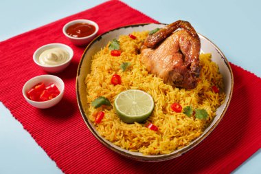 Mavi arka planda geleneksel tavuk biryani kasesi.