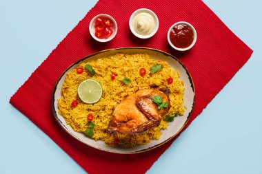 Mavi arka planda geleneksel tavuk biryani kasesi.