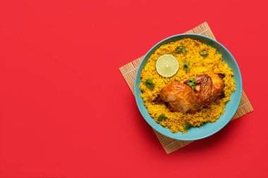 Kırmızı arka planda bir kase geleneksel tavuk biryani.
