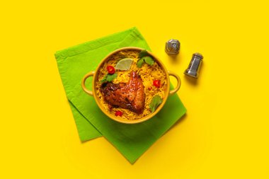 Sarı arka planda bir kase geleneksel tavuk biryani.