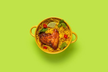 Yeşil arka planda geleneksel tavuk biryani kasesi.