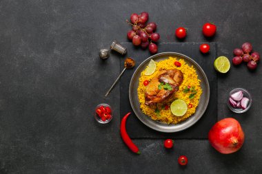Siyah arka planda malzemelerle geleneksel tavuk biryani tabağı.