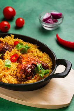 Yeşil arka planda malzemeleri olan geleneksel tavuk biryani pişirme yemeği, yakın plan.