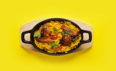 Sarı arka planda geleneksel tavuk biryani pişirme yemeği.