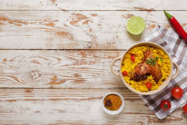 Beyaz ahşap arka planda malzemeli geleneksel tavuk biryani kasesi.