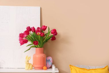 Laleli vazo, Paskalya yumurtası ve bej duvarın yanındaki rafta resim.