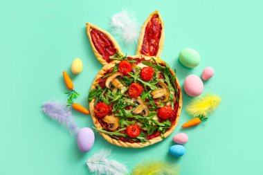 Turkuaz arka planda Paskalya kutlaması için lezzetli pizza ve yumurta boyalı kompozisyon