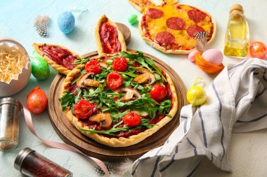 Mavi arka planda Paskalya kutlaması için lezzetli pizza ve yumurta kompozisyonu