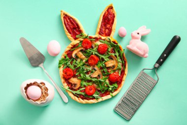 Turkuaz arka planda Paskalya kutlaması için lezzetli pizza ve yumurta boyalı kompozisyon