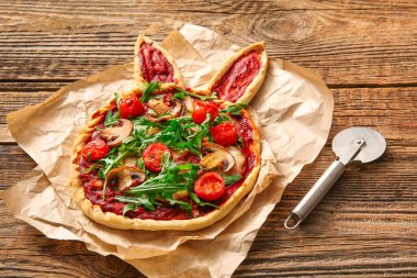 Tahta arka planda lezzetli pizza ve kesici. Paskalya kutlaması