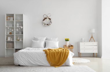 Paskalya çelengi ve raf ünitesiyle aydınlık yatak odasının içinde.