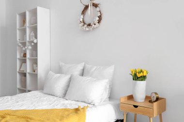 Paskalya çelengi ve raf ünitesiyle aydınlık yatak odasının içinde.