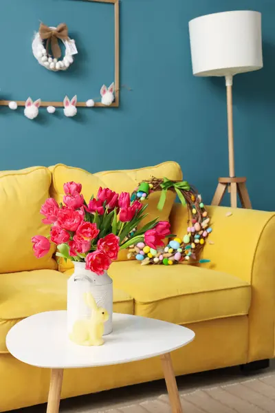 Vase with tulips and Easter rabbit on table in living room