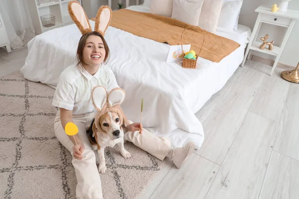 Young woman with Beagle dog and paper Easter eggs in bedroom