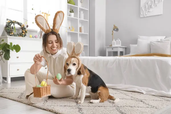 Young woman with Beagle dog and Easter eggs in bedroom