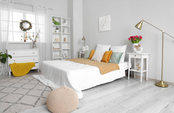 Интерьер светлой спальни с пасхальным венком и столами