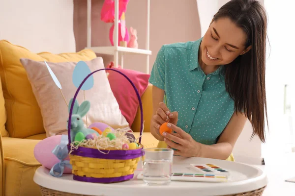 Evde Paskalya yumurtası boyayan genç bir kadın.