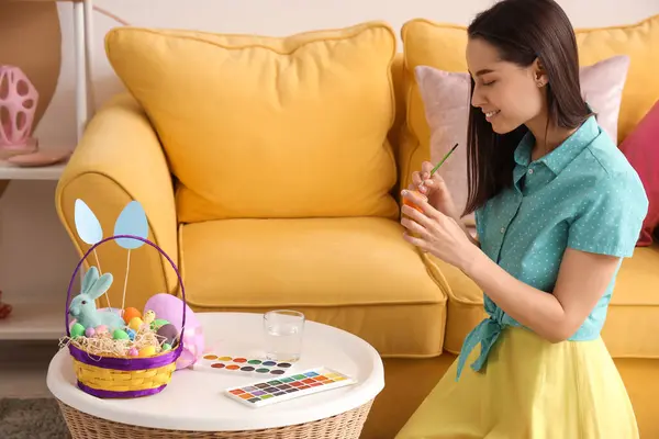 Evde Paskalya yumurtası boyayan genç bir kadın.